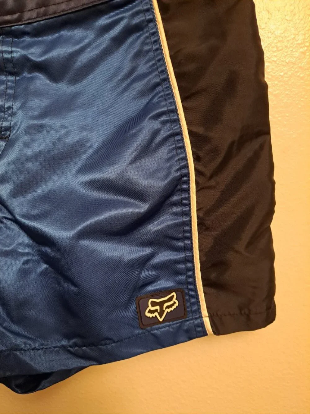Vintage Fox Racing board shorts featuring a blue satin finish &white piping.